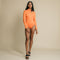 Orange, fitted, long sleeve bodysuit has cutaway detail on front. 